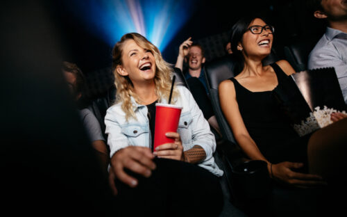 Young,people,laughing,while,watching,film,in,movie,theater.,group
